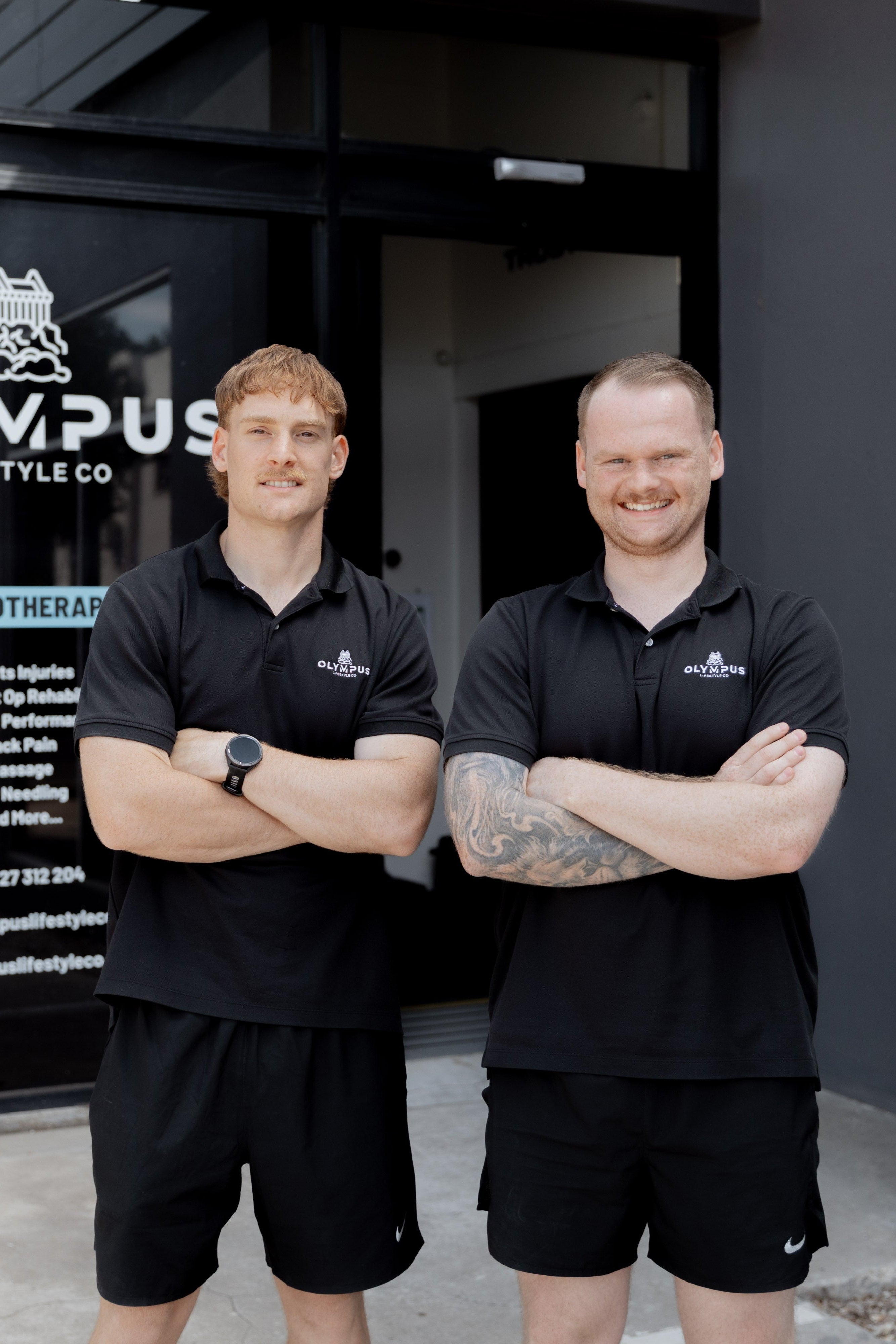 Two physiotherapists standing outside a building with 'Olympus Lifestyle Co' branding.